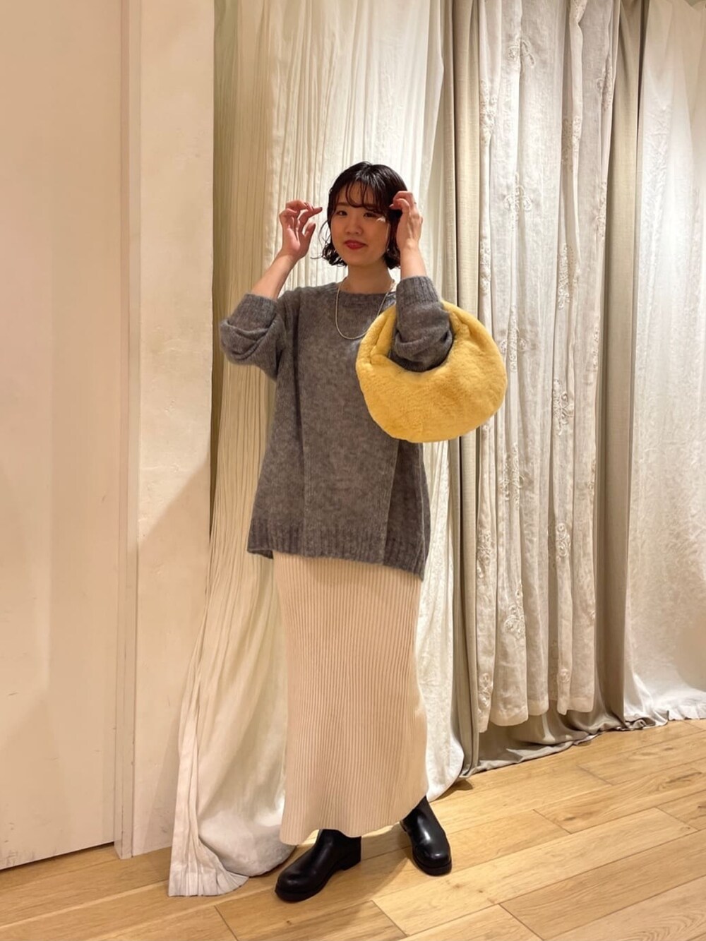 ブルー系のニット/セーター、オレンジ系のハンドバッグ、ホワイト系のスカートを着用したレディースの秋コーディネートの2枚目の写真