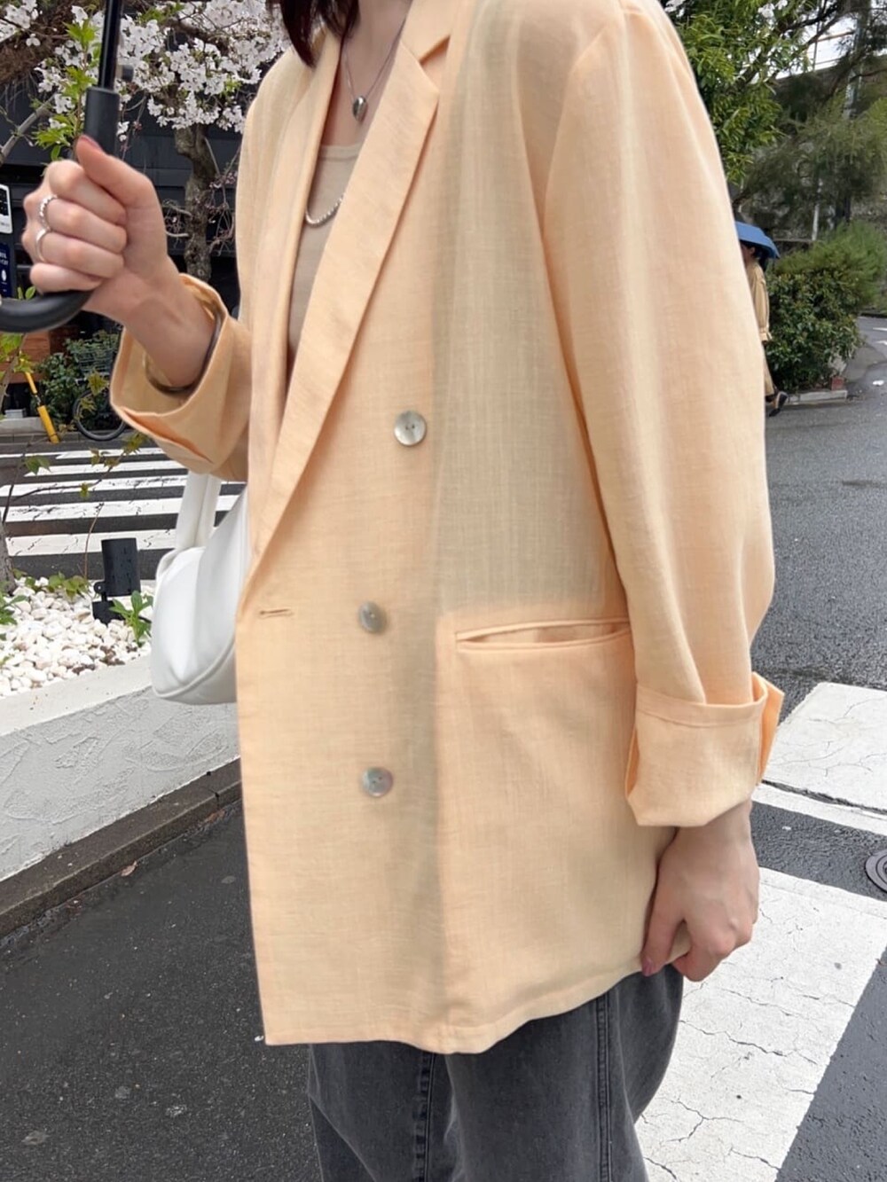 イエロー系のテーラードジャケット、ブラック系のデニムパンツ、シルバー系のネックレスを着用したレディースの春コーディネートの3枚目の写真