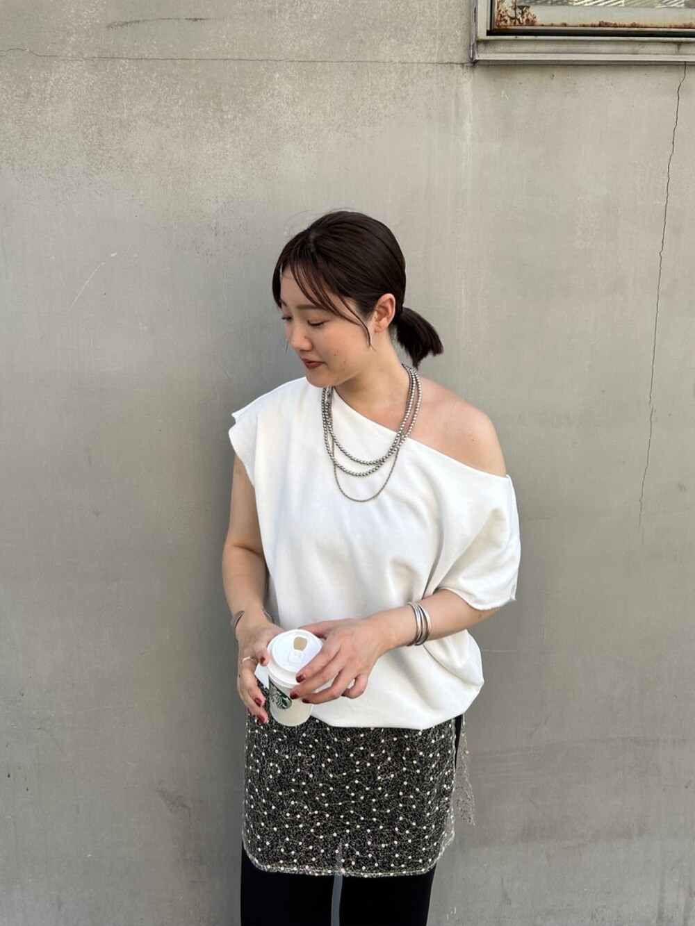 ホワイト系のスウェット、ゴールド系のスカート、ブラック系のその他パンツを着用したレディースの夏コーディネートの3枚目の写真