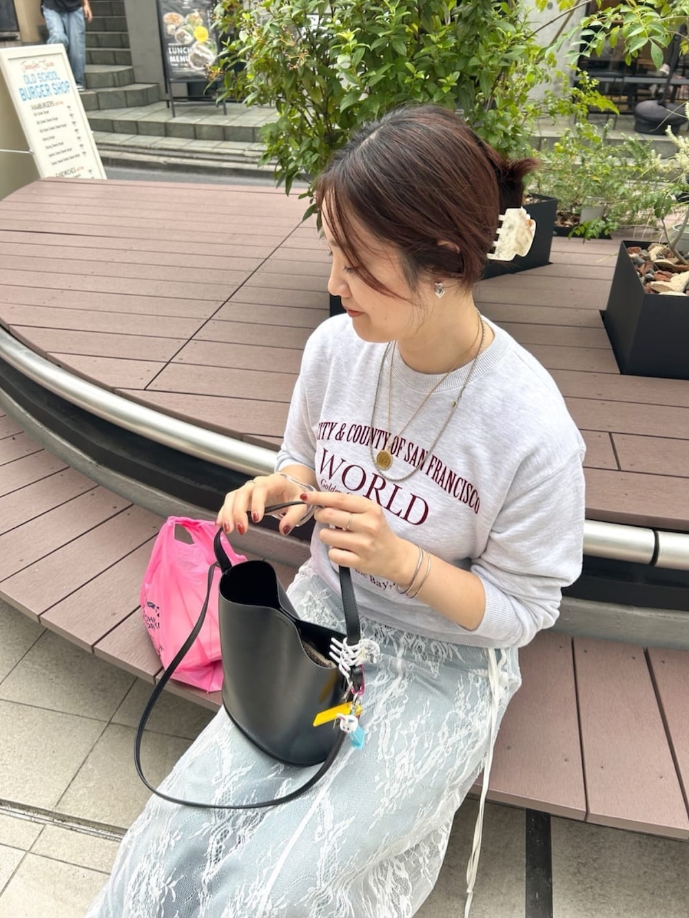 グレー系のTシャツ/カットソー、ブラック系のスカート、ブルー系のデニムパンツを着用したレディースの秋コーディネートの3枚目の写真
