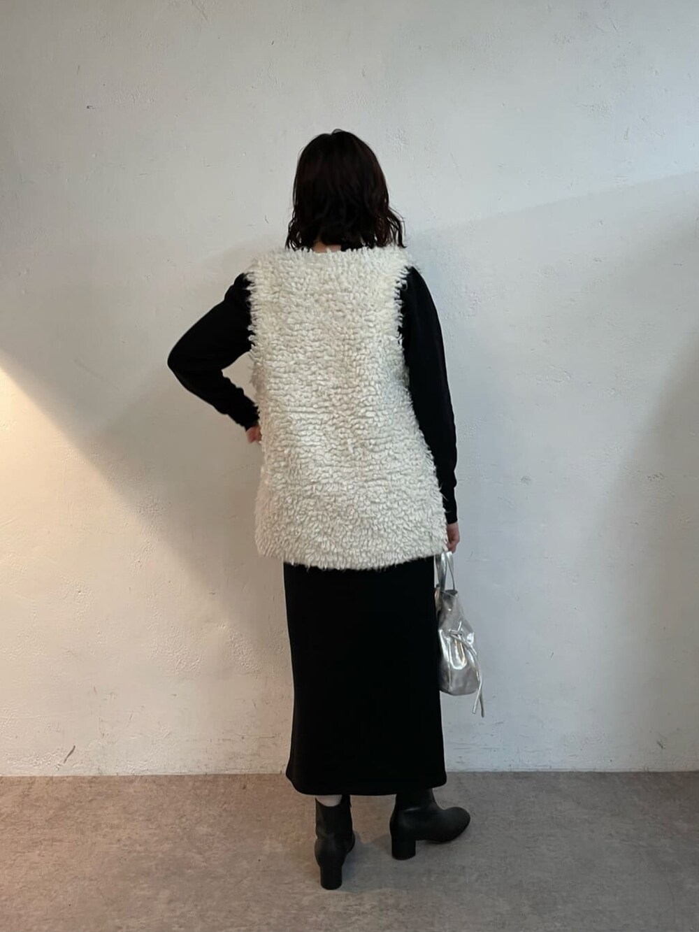 シルバー系のトートバッグ、ブラック系のブーツ、ホワイト系のニット/セーターを着用したレディースの冬コーディネートの4枚目の写真