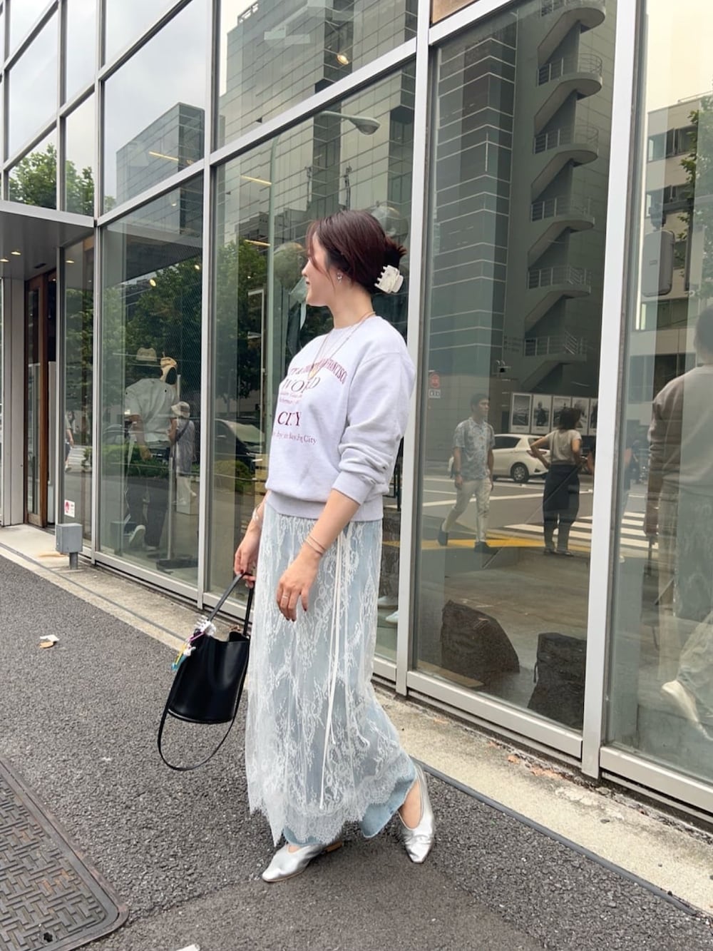 グレー系のTシャツ/カットソー、ブラック系のスカート、ブルー系のデニムパンツを着用したレディースの秋コーディネートの2枚目の写真
