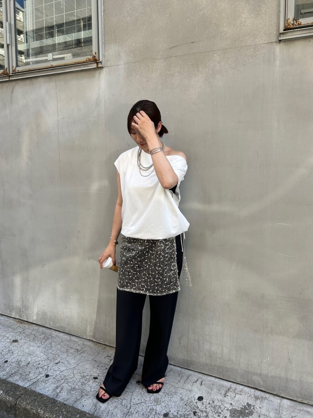 ホワイト系のスウェット、ゴールド系のスカート、ブラック系のその他パンツを着用したレディースの夏コーディネートの2枚目の写真