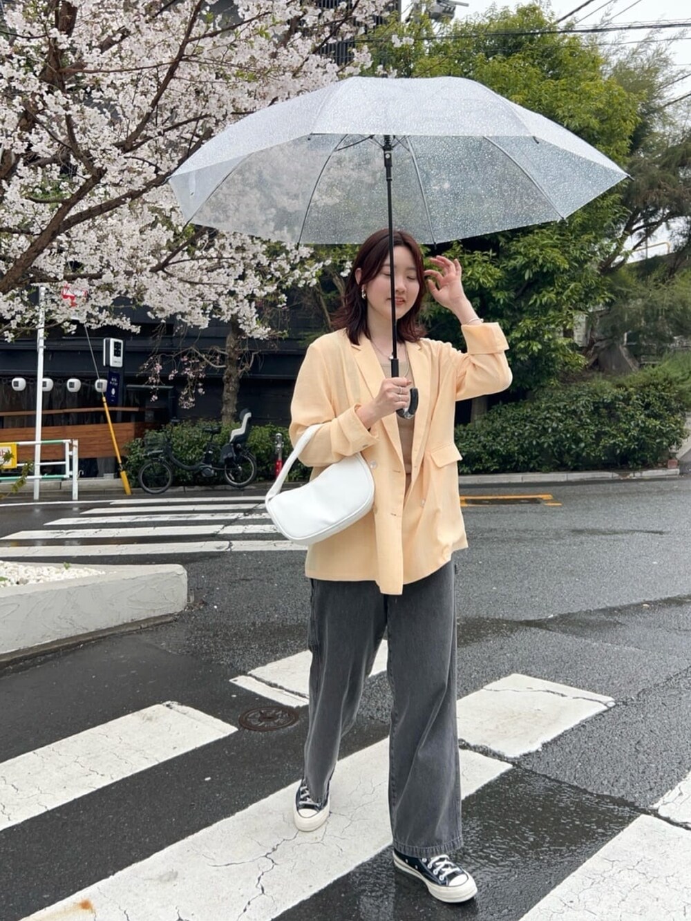 イエロー系のテーラードジャケット、ブラック系のデニムパンツ、シルバー系のネックレスを着用したレディースの春コーディネートの2枚目の写真