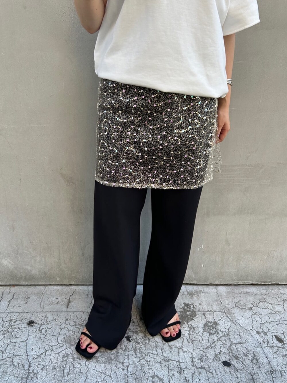 ホワイト系のスウェット、ゴールド系のスカート、ブラック系のその他パンツを着用したレディースの夏コーディネートの4枚目の写真