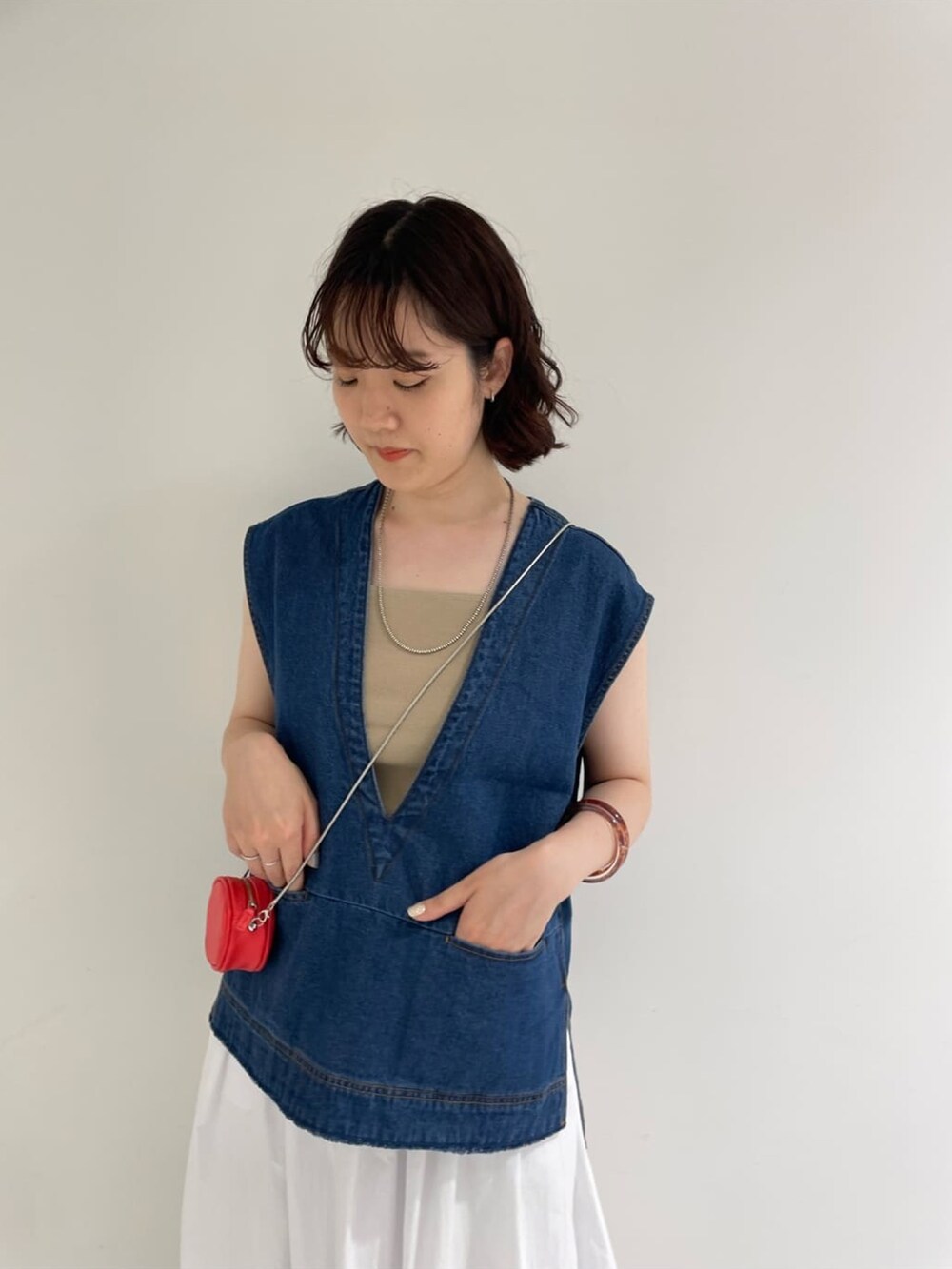 ホワイト系のスカート、ブルー系のベスト、ベージュ系のキャミソールを着用したレディースの夏コーディネートの4枚目の写真