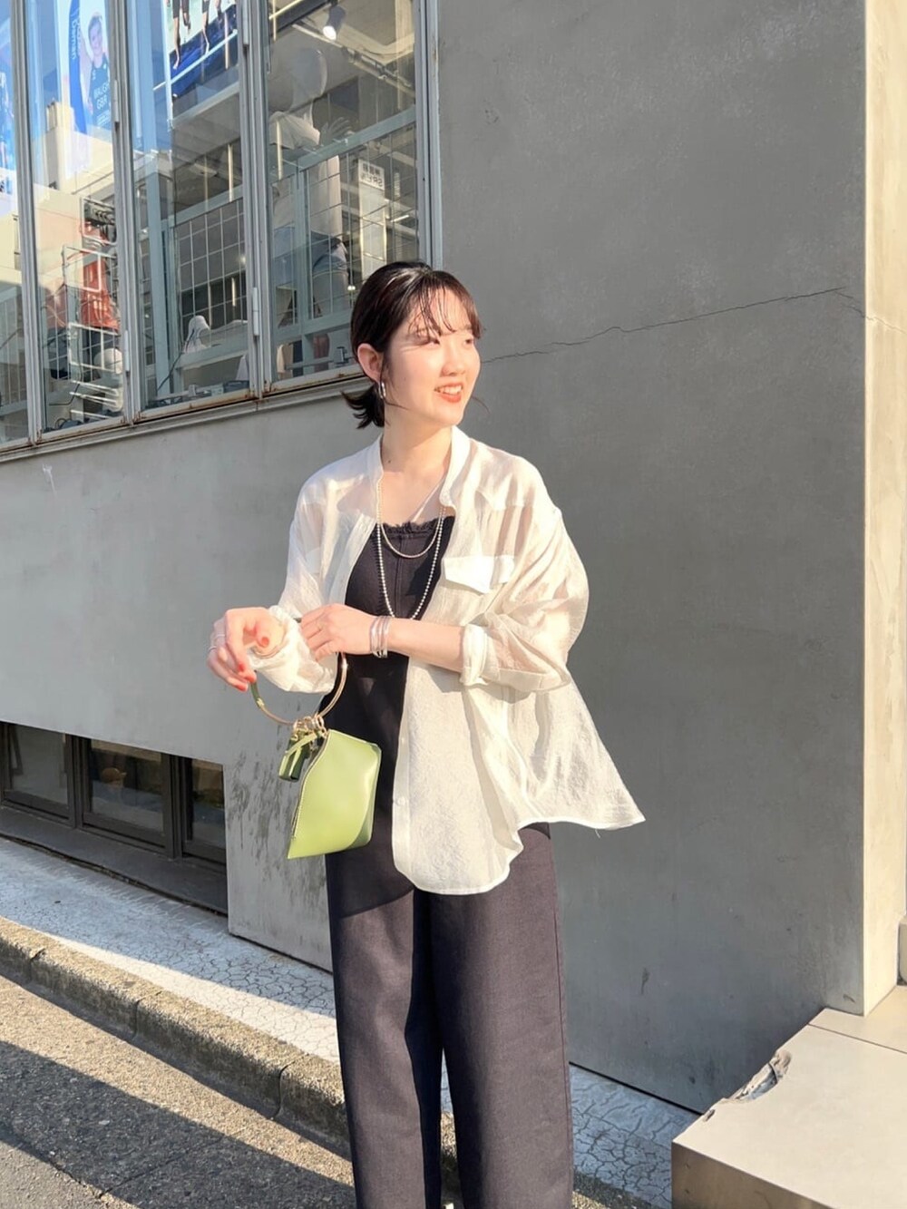 ホワイト系のシャツ/ブラウス、グレー系のサロペット/オーバーオール、ブラック系のハンドバッグを着用したレディースの春コーディネートの3枚目の写真