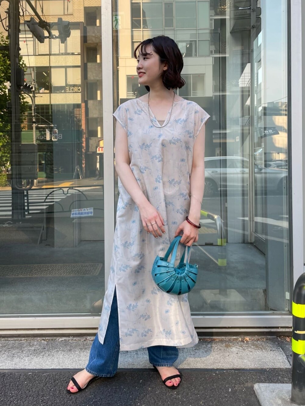 ベージュ系のワンピース、オレンジ系のトートバッグ、ブルー系のデニムパンツを着用したレディースの夏コーディネートの3枚目の写真