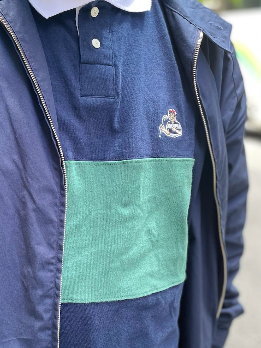 ブルー系のポロシャツ、ブルー系のブルゾン、グレー系のスラックスを着用したメンズの春コーディネートの2枚目の写真