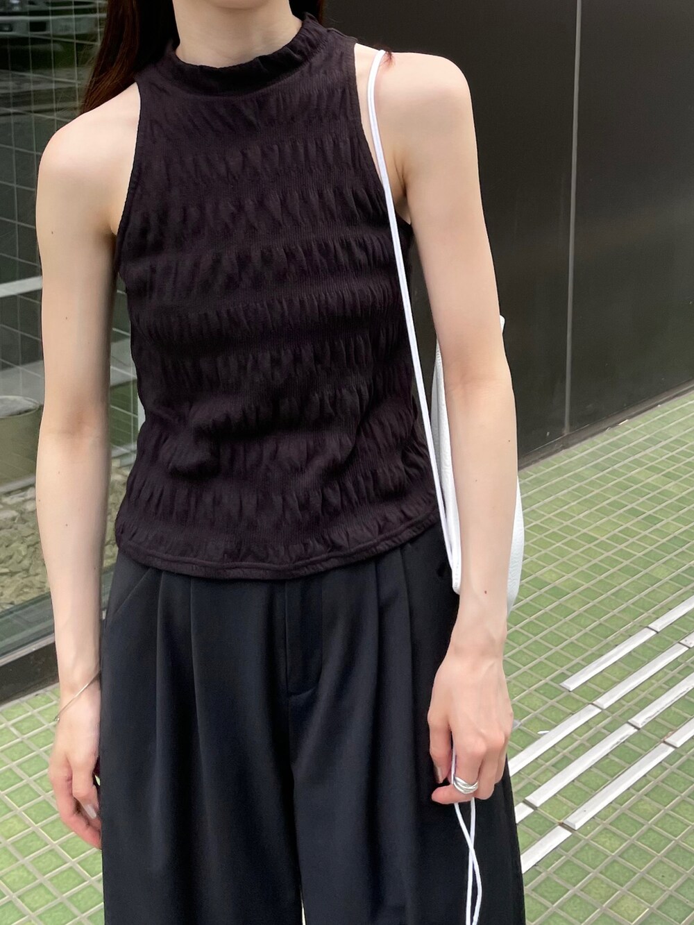 ブラック系のTシャツ/カットソー、ブラック系のスラックス、ホワイト系のスニーカーを着用したレディースの夏コーディネートの2枚目の写真