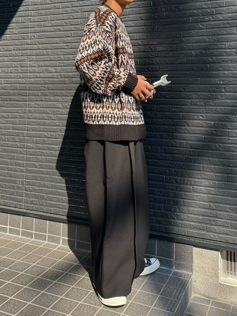 ブラウン系のニット/セーター、ブラック系のスラックスを着用したメンズの秋コーディネートの4枚目の写真