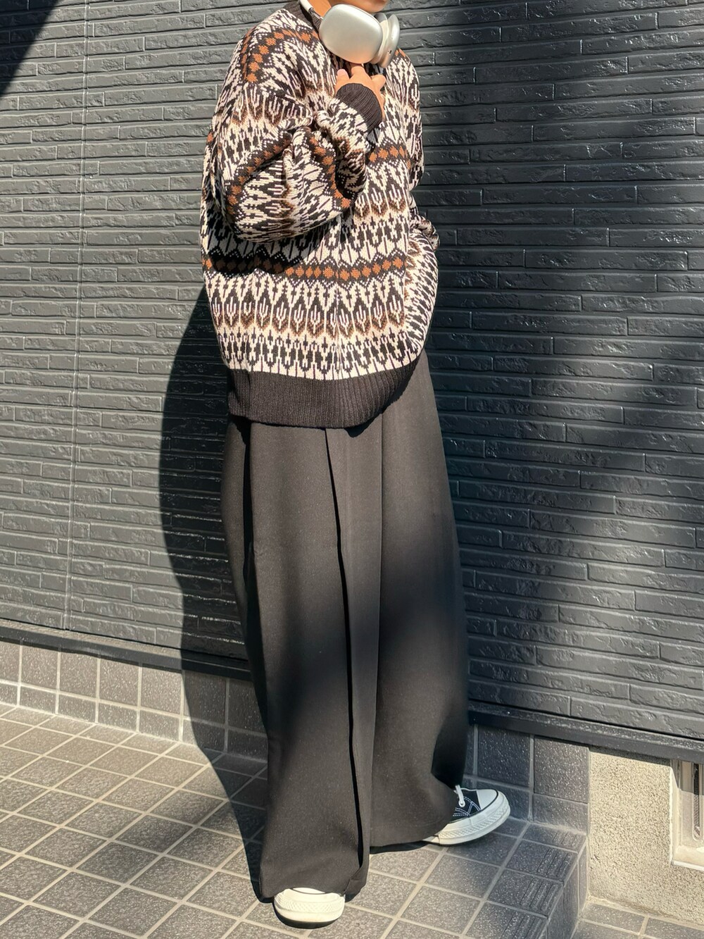 ブラウン系のニット/セーター、ブラック系のスラックスを着用したメンズの秋コーディネートの2枚目の写真