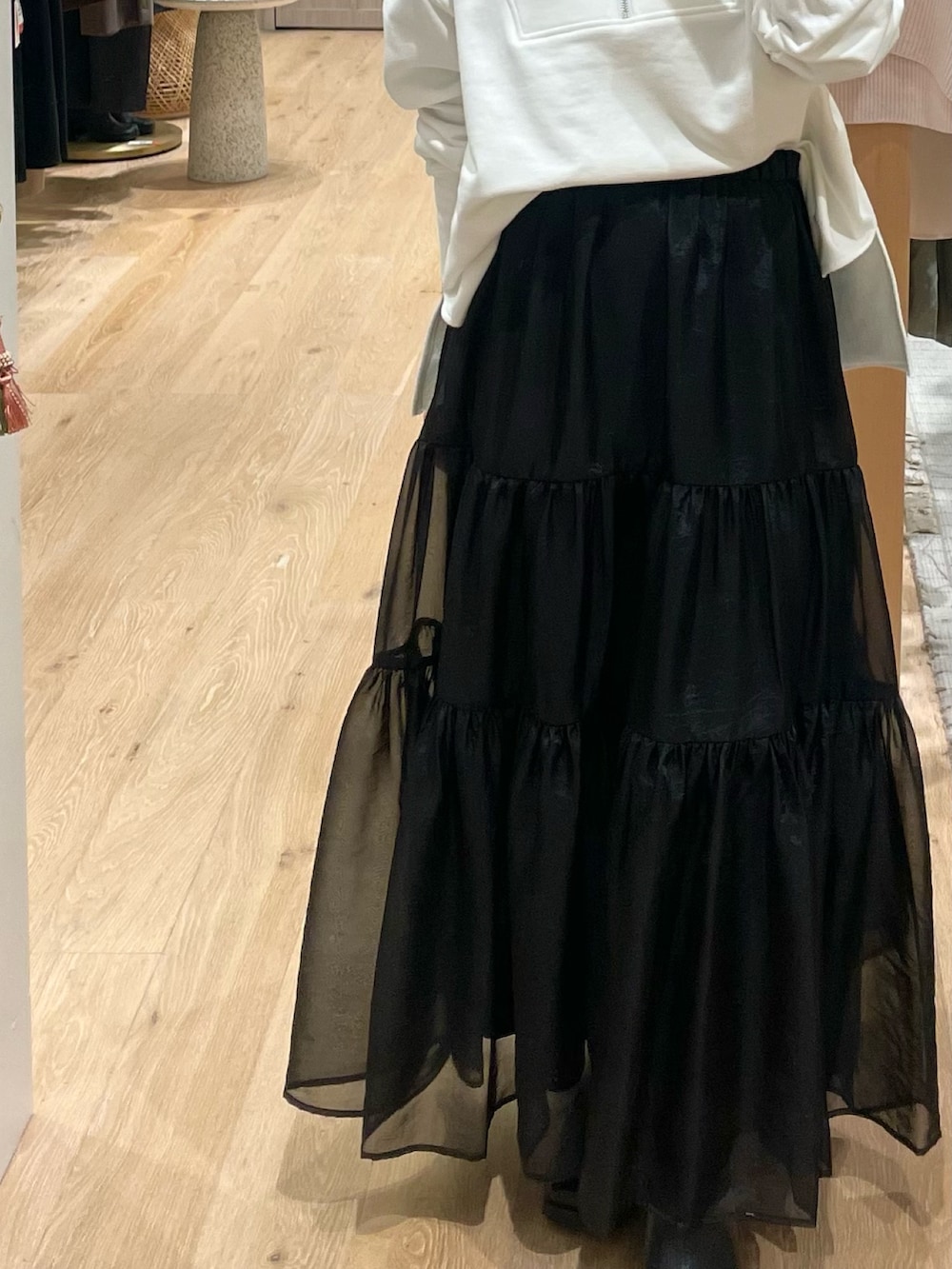 ブラック系のスカート、ホワイト系のスウェット、ブラック系のその他シューズを着用したレディースの春コーディネートの3枚目の写真