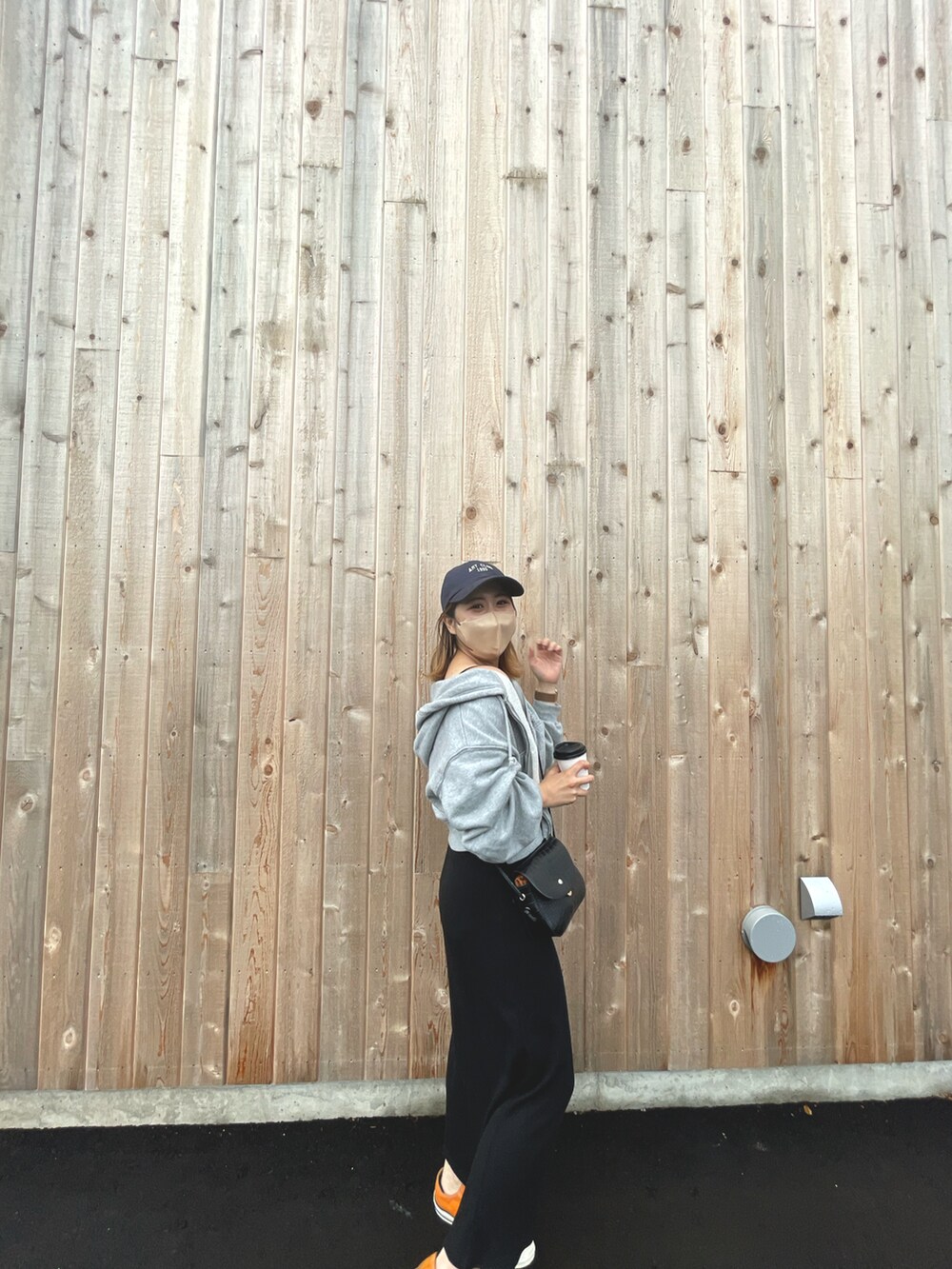 ブラック系のワンピース、オレンジ系のスニーカー、ブラック系のショルダーバッグを着用したレディースの秋コーディネートの2枚目の写真