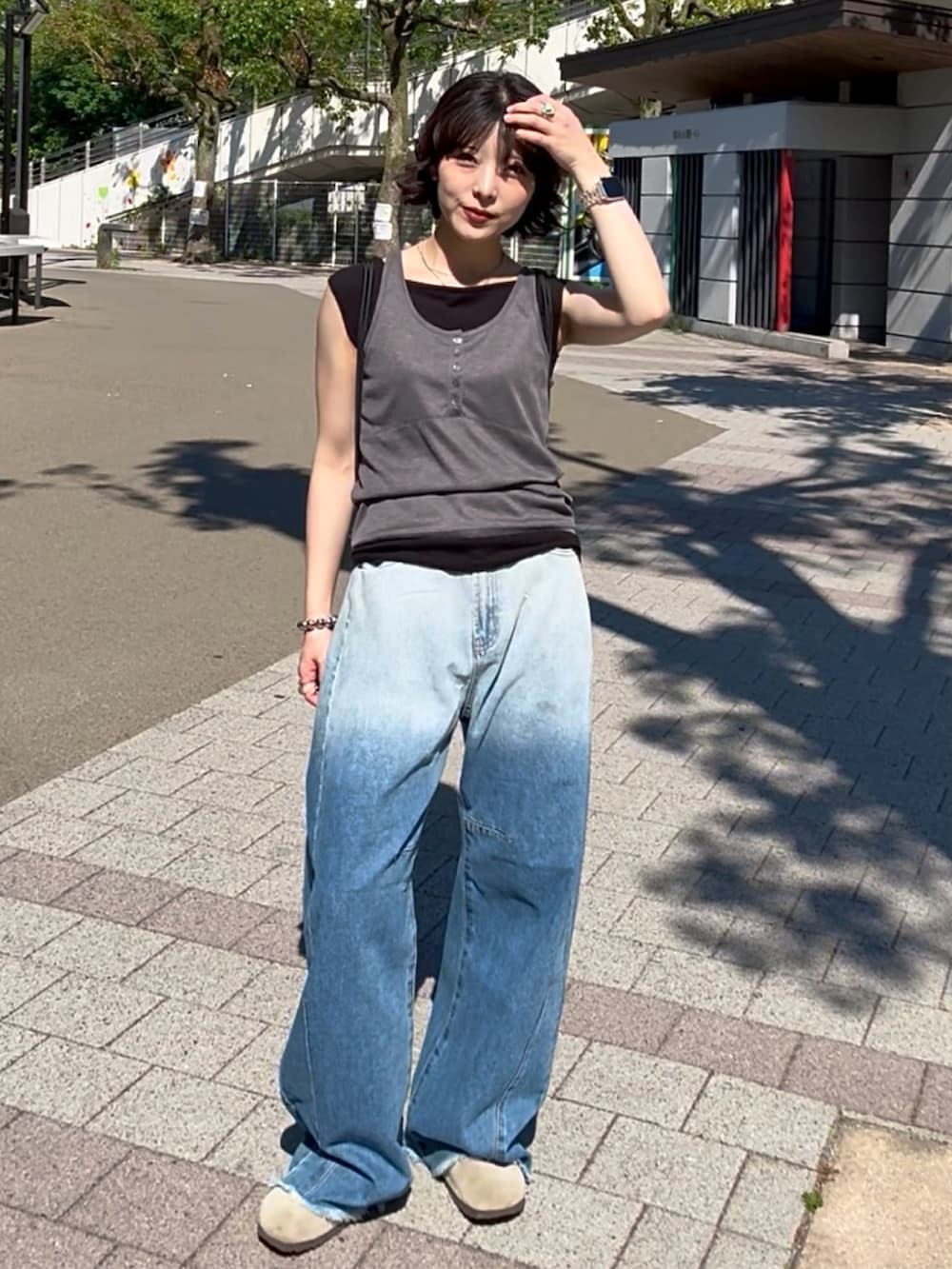 ブルー系のデニムパンツ、ベージュ系のサンダル、ブラック系のトップスを着用したレディースの夏コーディネートの2枚目の写真