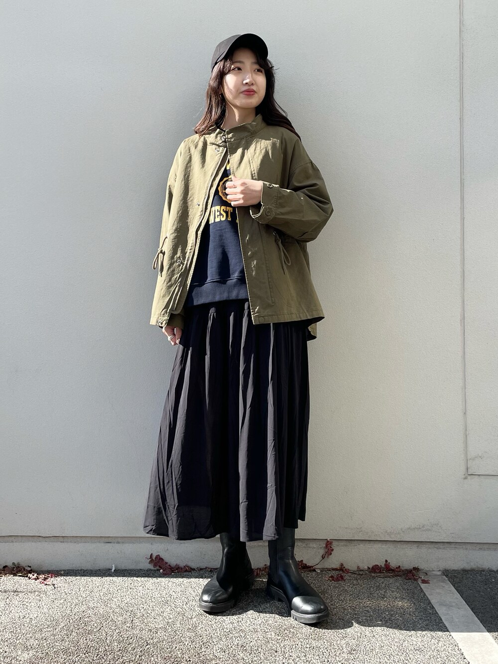 グリーン系のミリタリージャケット、ブラック系のワンピース、ブラック系のキャップを着用したレディースの冬コーディネートの2枚目の写真