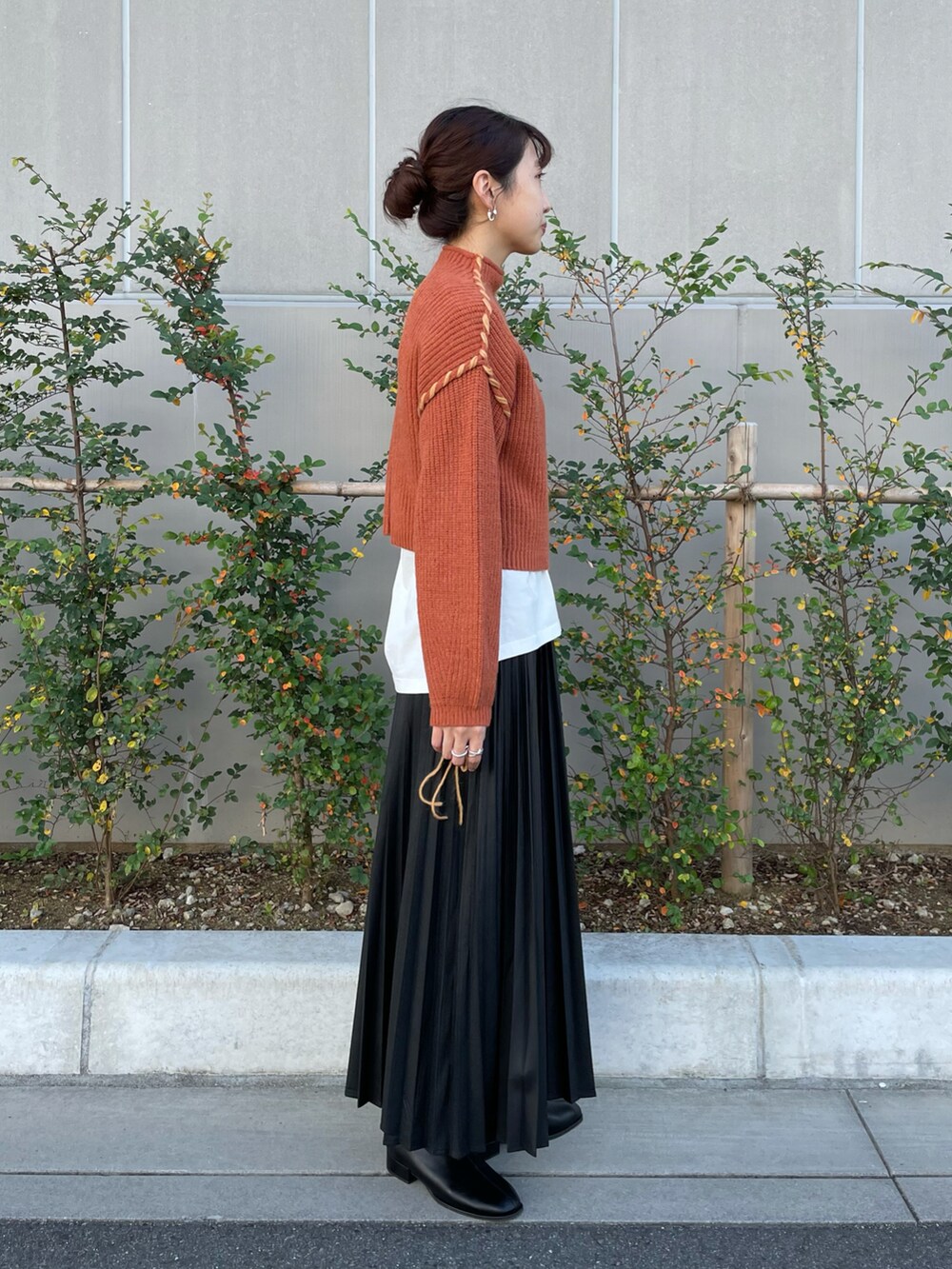 ピンク系のニット/セーター、ベージュ系のTシャツ/カットソー、ブラック系のスカートを着用したレディースの秋コーディネートの2枚目の写真