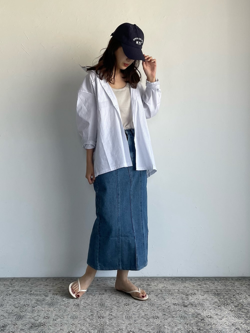 ホワイト系のシャツ/ブラウス、ブルー系のデニムスカート、ブルー系のキャップを着用したレディースの夏コーディネートの3枚目の写真