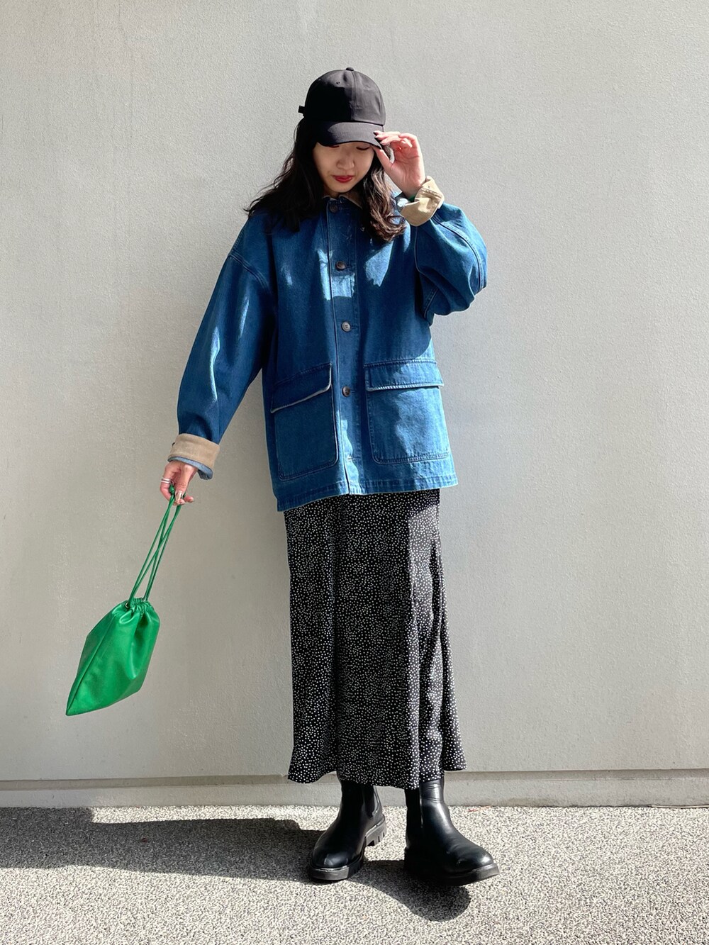 ブルー系のカバーオール、ブラック系のスカート、グリーン系のショルダーバッグを着用したレディースの春コーディネートの2枚目の写真