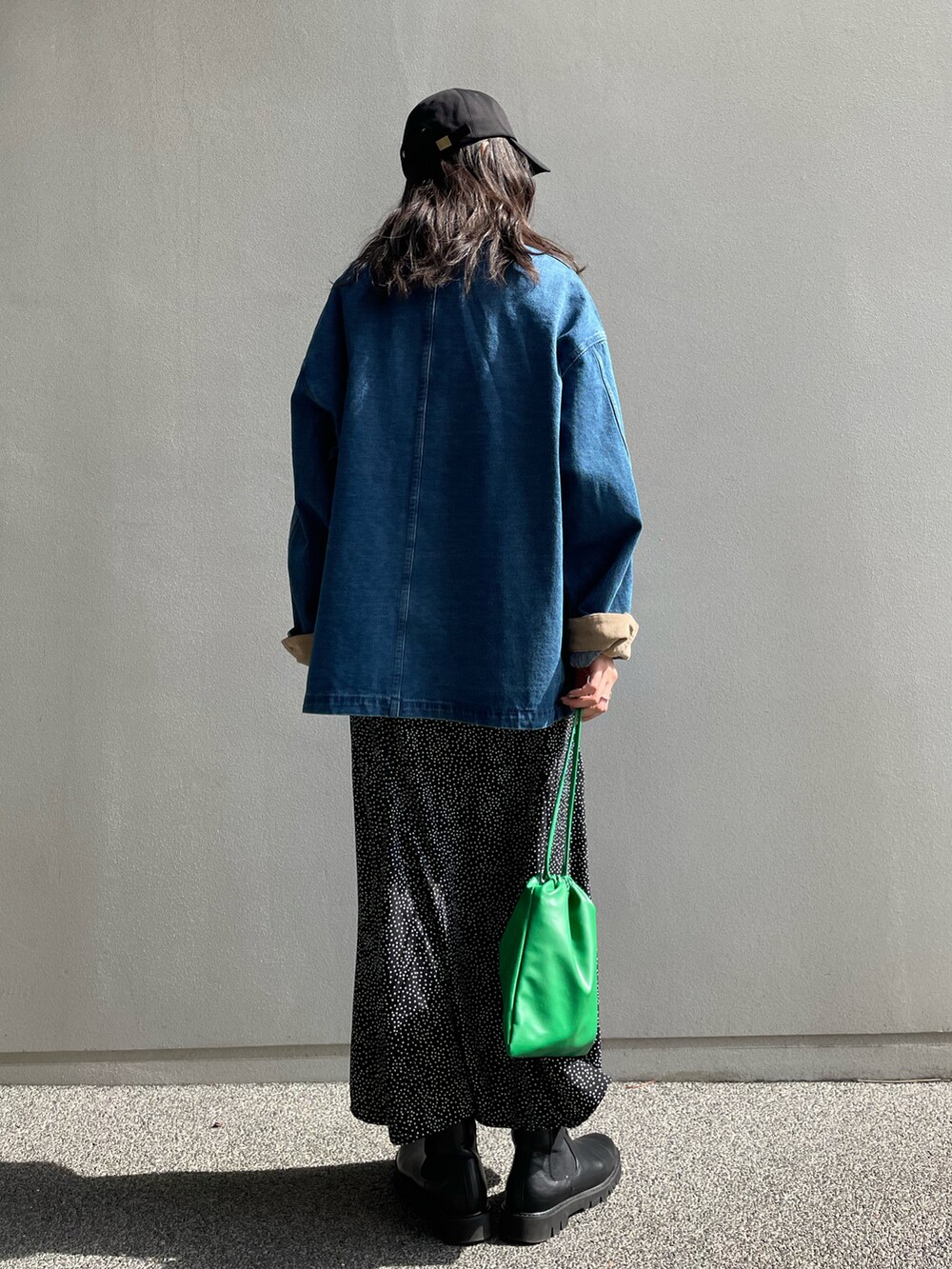 ブルー系のカバーオール、ブラック系のスカート、グリーン系のショルダーバッグを着用したレディースの春コーディネートの4枚目の写真