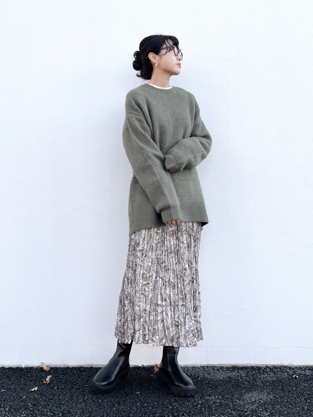 グリーン系のニット/セーター、ベージュ系のスカート、ベージュ系のTシャツ/カットソーを着用したレディースの秋コーディネートの2枚目の写真