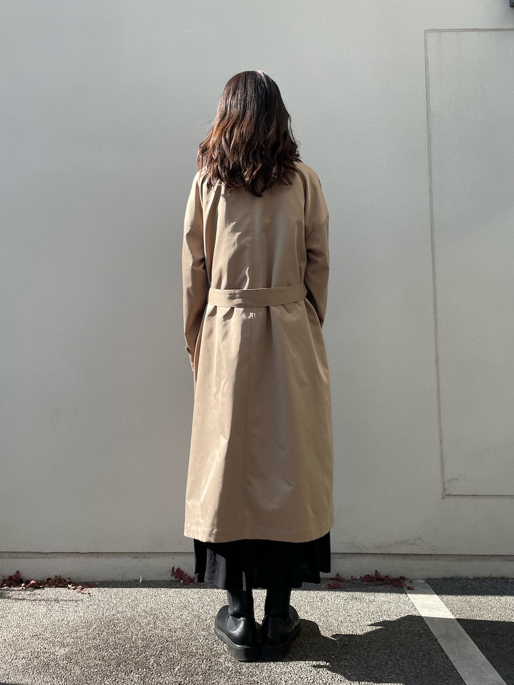 ベージュ系のステンカラーコート、ブラック系のワンピースを着用したレディースの冬コーディネートの3枚目の写真