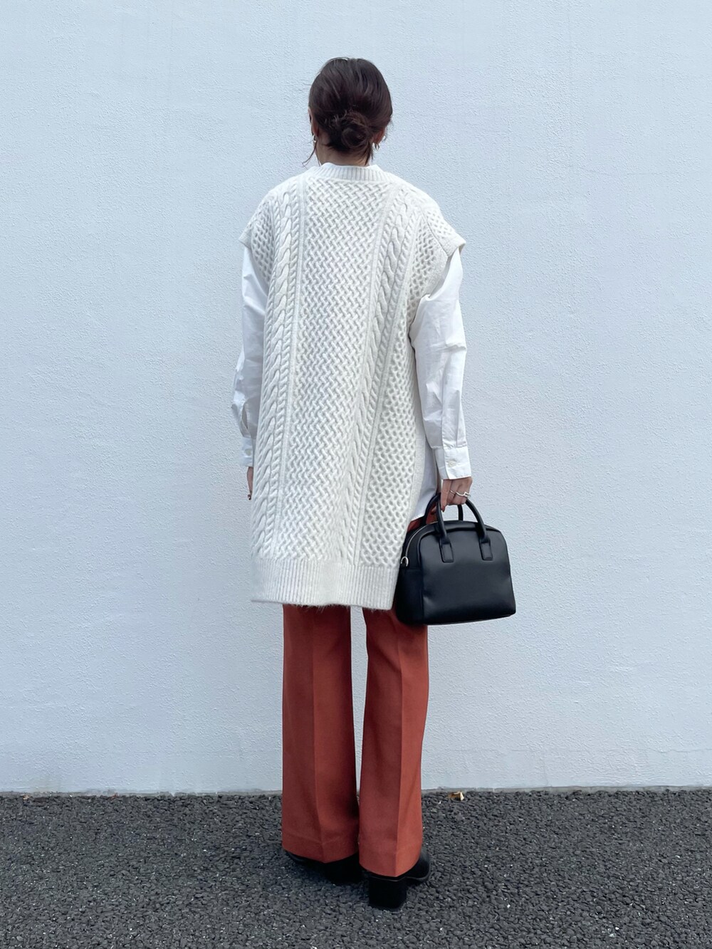 ホワイト系のベスト、オレンジ系のその他パンツ、ブラック系のボストンバッグを着用したレディースの秋コーディネートの3枚目の写真