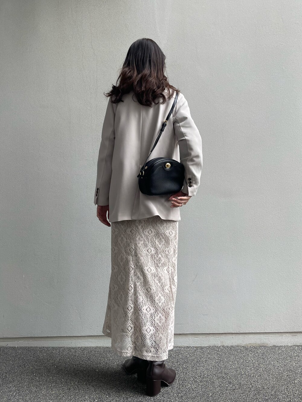 ベージュ系のテーラードジャケット、ブラウン系のニット/セーター、ブラック系のブーツを着用したレディースの冬コーディネートの2枚目の写真