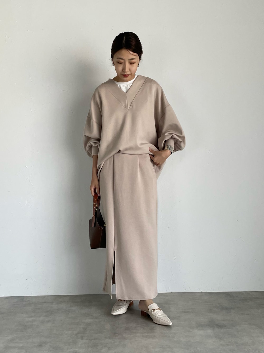 ブラウン系のスウェット、ベージュ系のスカート、ブラウン系のハンドバッグを着用したレディースの夏コーディネートの2枚目の写真