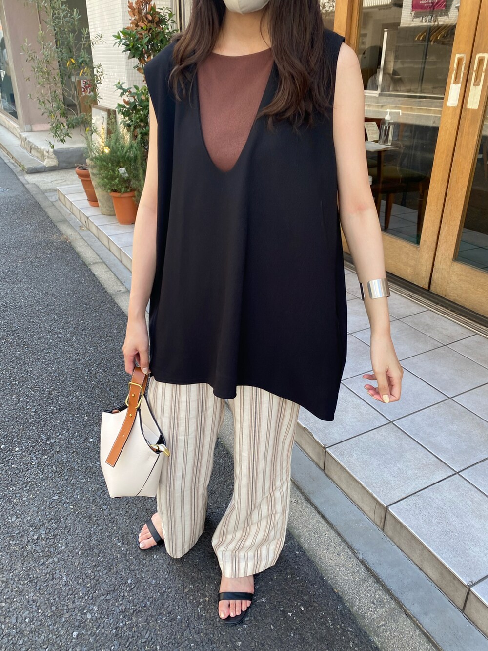 ブラック系のベスト、ホワイト系のハンドバッグ、ベージュ系のハットを着用したレディースの夏コーディネートの3枚目の写真