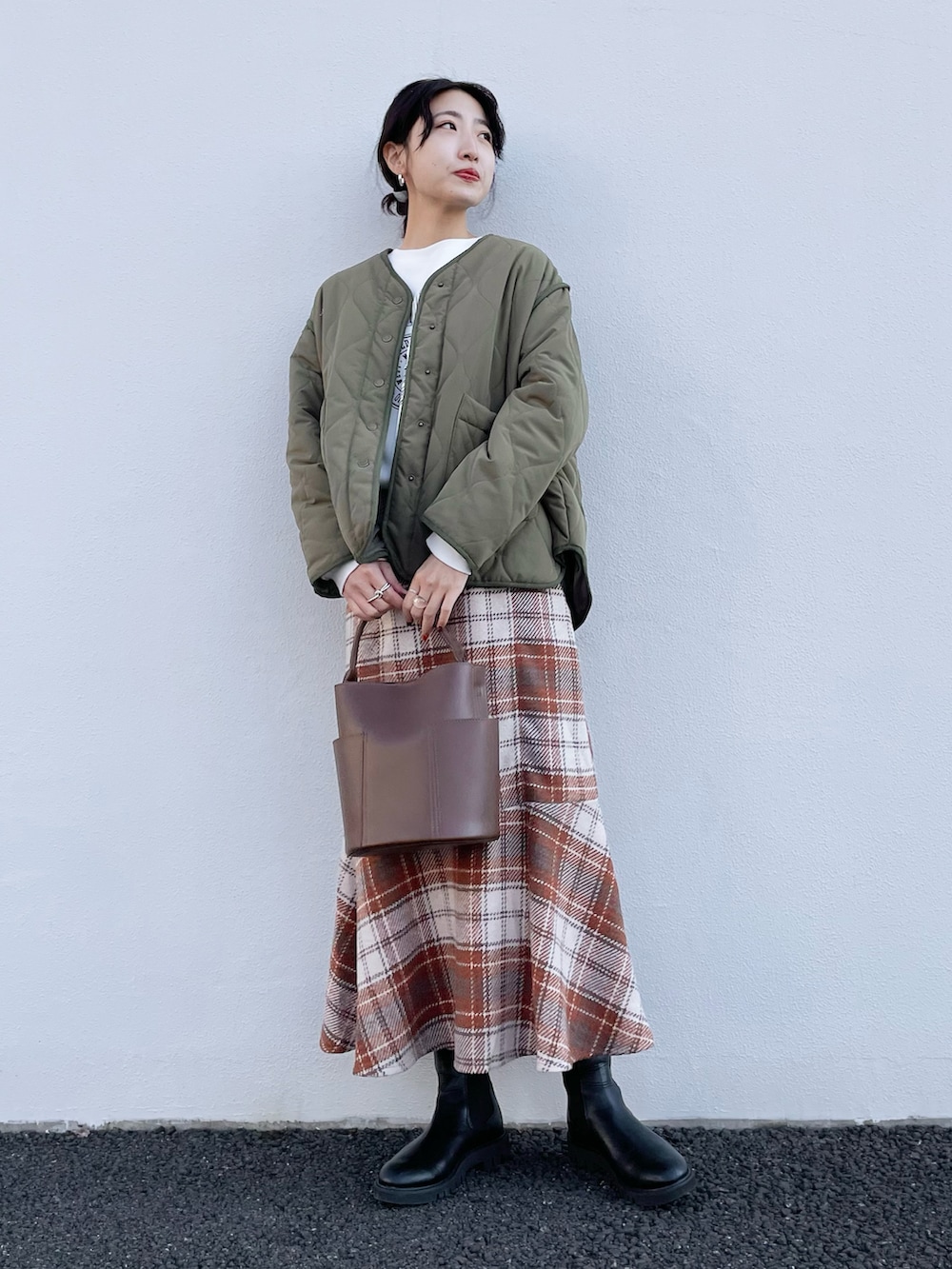 ホワイト系のナイロンジャケット、ブラウン系のスカート、ブラック系のスウェットを着用したレディースの冬コーディネートの2枚目の写真