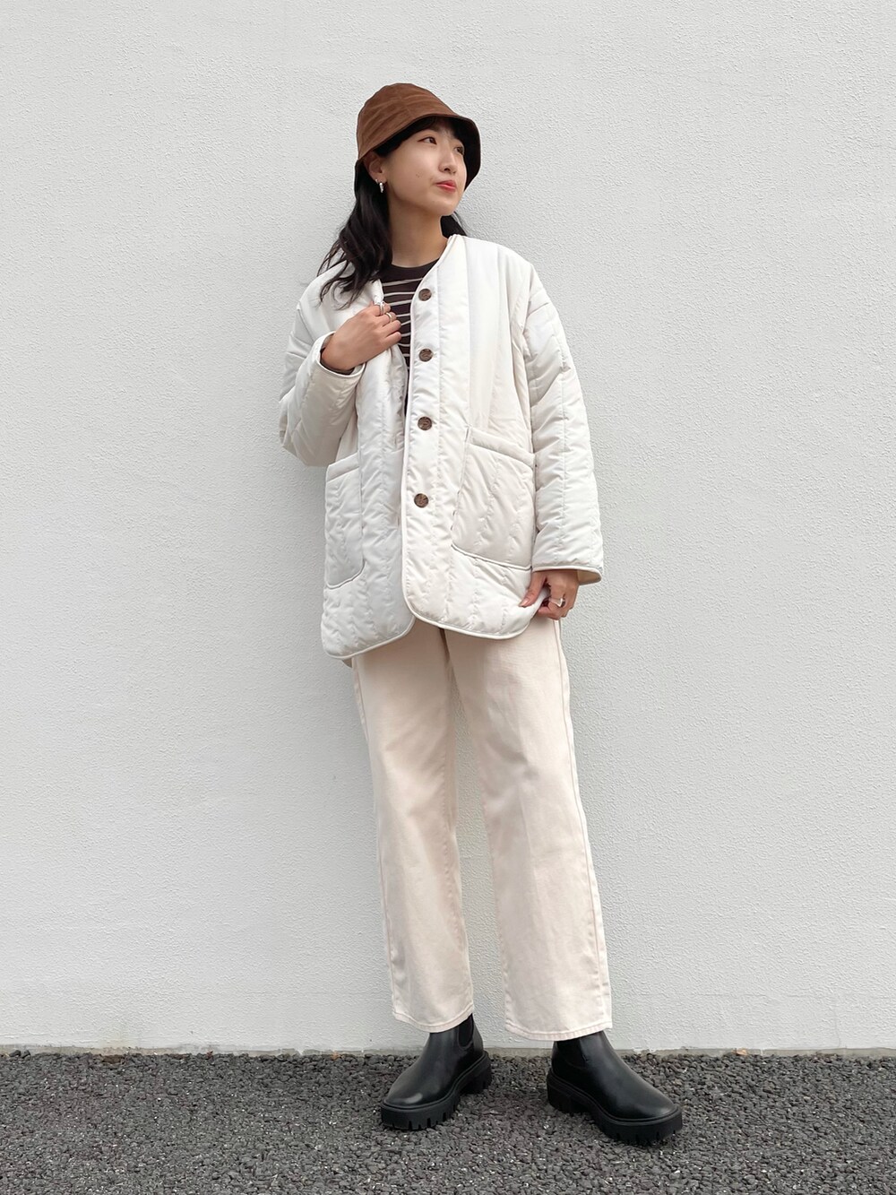ホワイト系のナイロンジャケット、ホワイト系のTシャツ/カットソー、ブラック系のブーツを着用したレディースの冬コーディネートの2枚目の写真