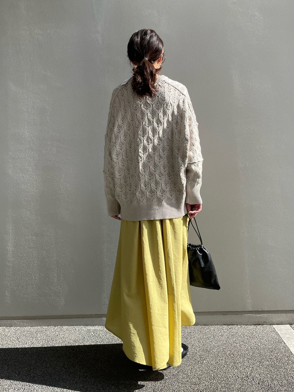 ホワイト系のニット/セーター、イエロー系のスカート、ブラック系のショルダーバッグを着用したレディースの冬コーディネートの2枚目の写真