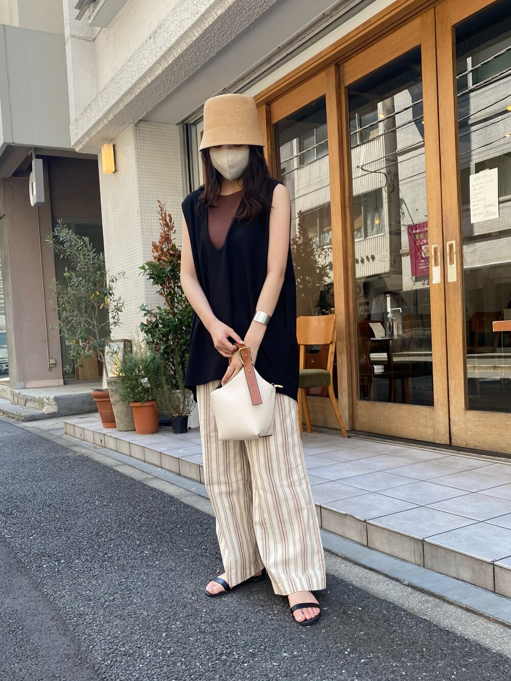 ブラック系のベスト、ホワイト系のハンドバッグ、ベージュ系のハットを着用したレディースの夏コーディネートの2枚目の写真