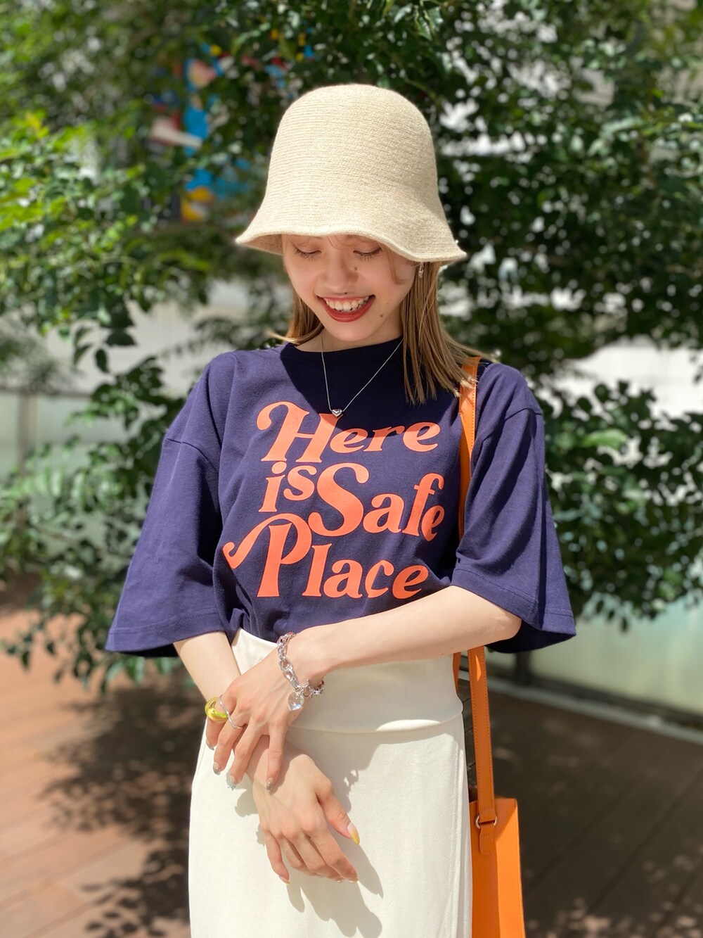 ブラック系のTシャツ/カットソー、オレンジ系のショルダーバッグ、ホワイト系のスカートを着用したレディースの夏コーディネートの5枚目の写真