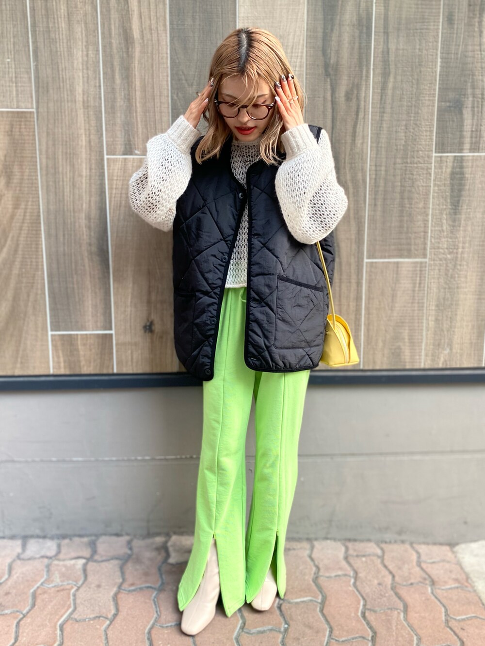 ホワイト系のカーディガン/ボレロ、イエロー系のバッグ、ブラック系のベストを着用したレディースの春コーディネートの2枚目の写真