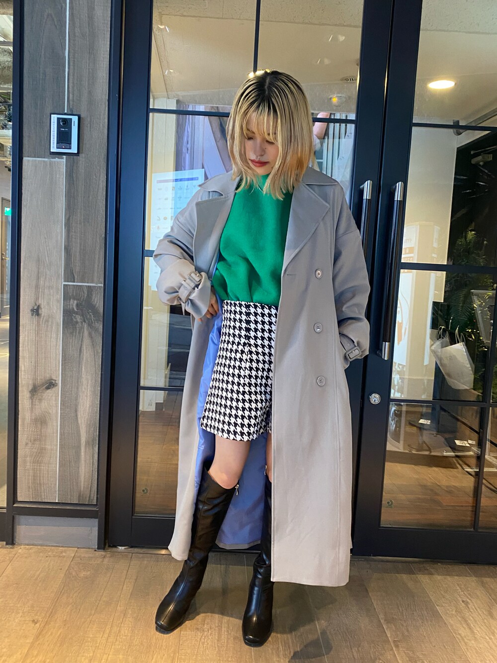 グリーン系のニット/セーター、ベージュ系のトレンチコート、ホワイト系のパンツを着用したレディースの秋コーディネートの3枚目の写真