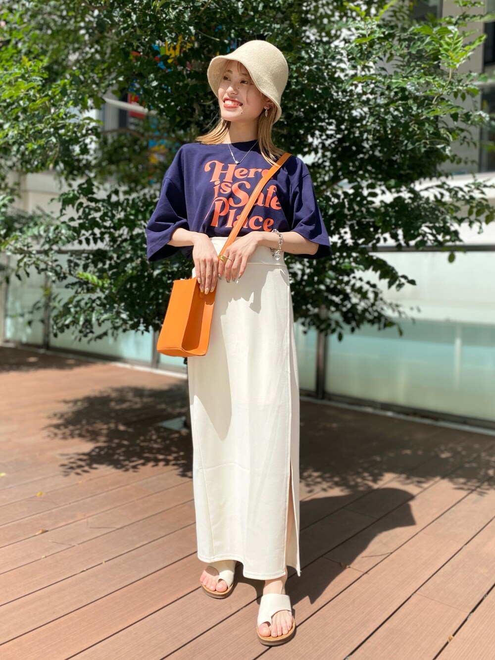 ブラック系のTシャツ/カットソー、オレンジ系のショルダーバッグ、ホワイト系のスカートを着用したレディースの夏コーディネートの3枚目の写真