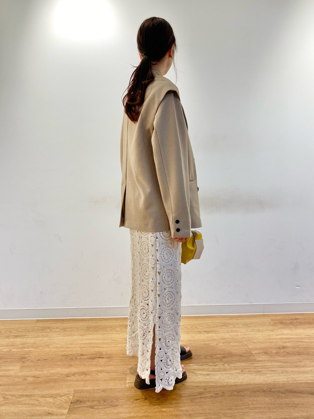 ホワイト系のスカート、ブラウン系のサンダル、ベージュ系のその他アウターを着用したレディースの春コーディネートの2枚目の写真