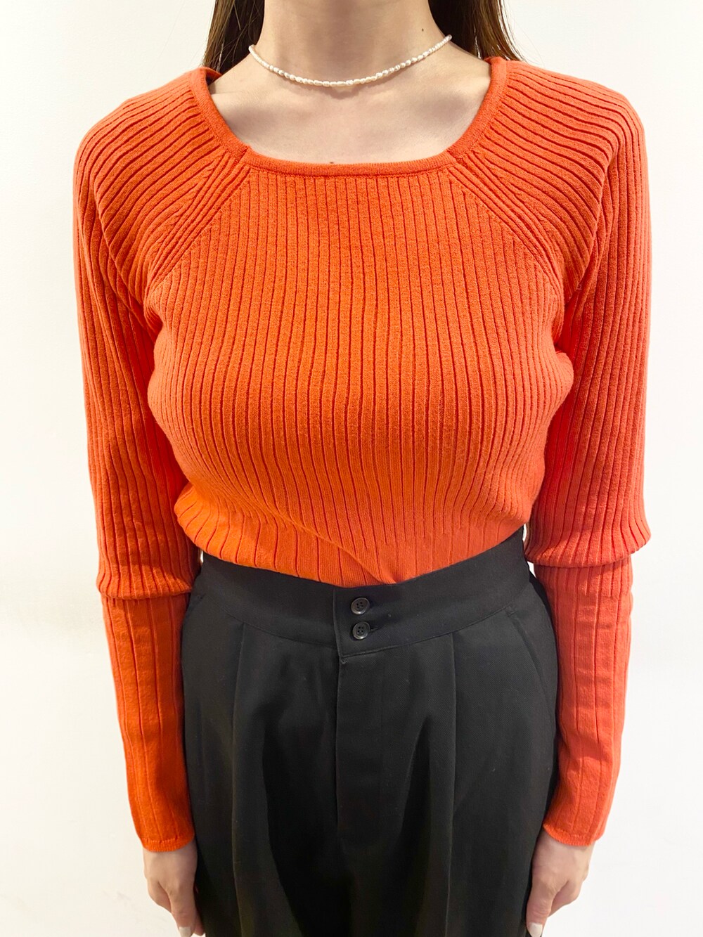 レッド系のニット/セーター、ブラック系のボディバッグ/ウエストポーチ、ホワイト系のブーツを着用したレディースの冬コーディネートの2枚目の写真