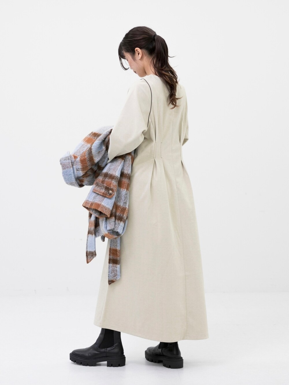 ブラック系のブーツ、ブルー系のステンカラーコート、ホワイト系のワンピースを着用したレディースの秋コーディネートの3枚目の写真