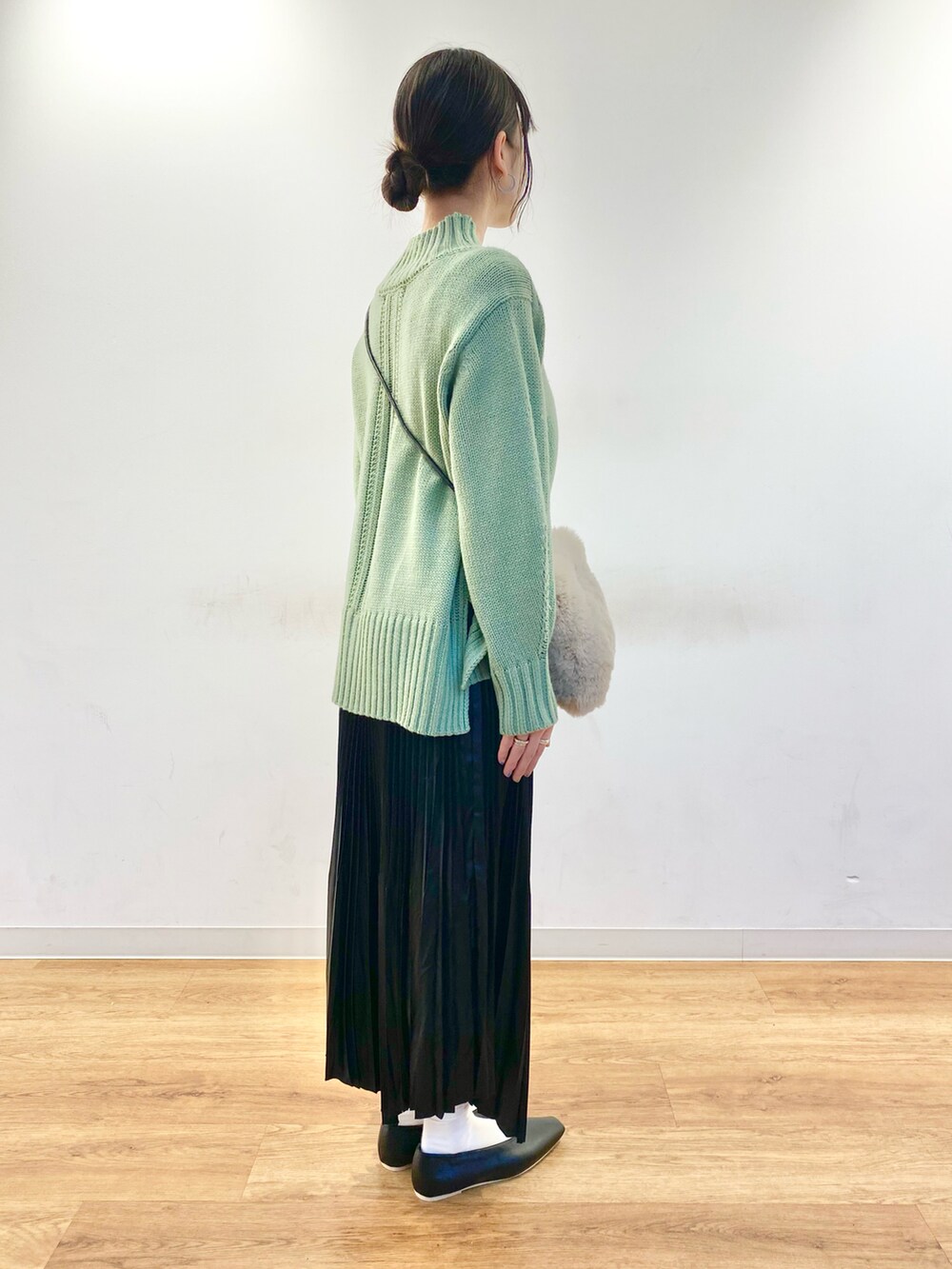 グリーン系のニット/セーター、ベージュ系のショルダーバッグ、ブラック系のスカートを着用したレディースの冬コーディネートの2枚目の写真