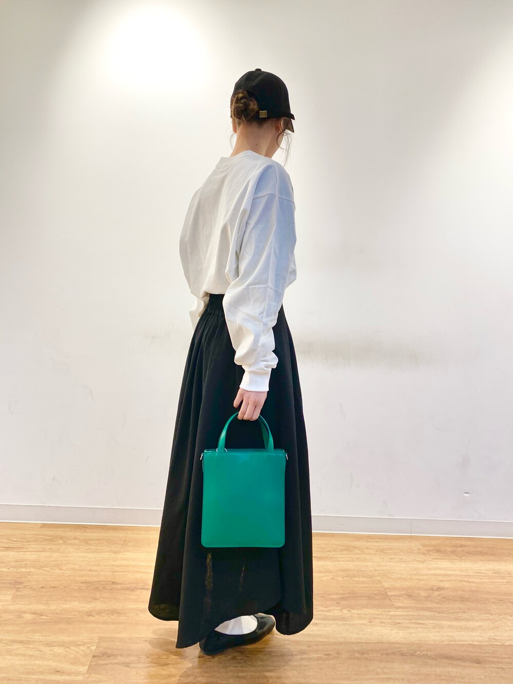 ブラック系のスカート、グリーン系のトートバッグ、ブラック系のその他シューズを着用したレディースの冬コーディネートの2枚目の写真