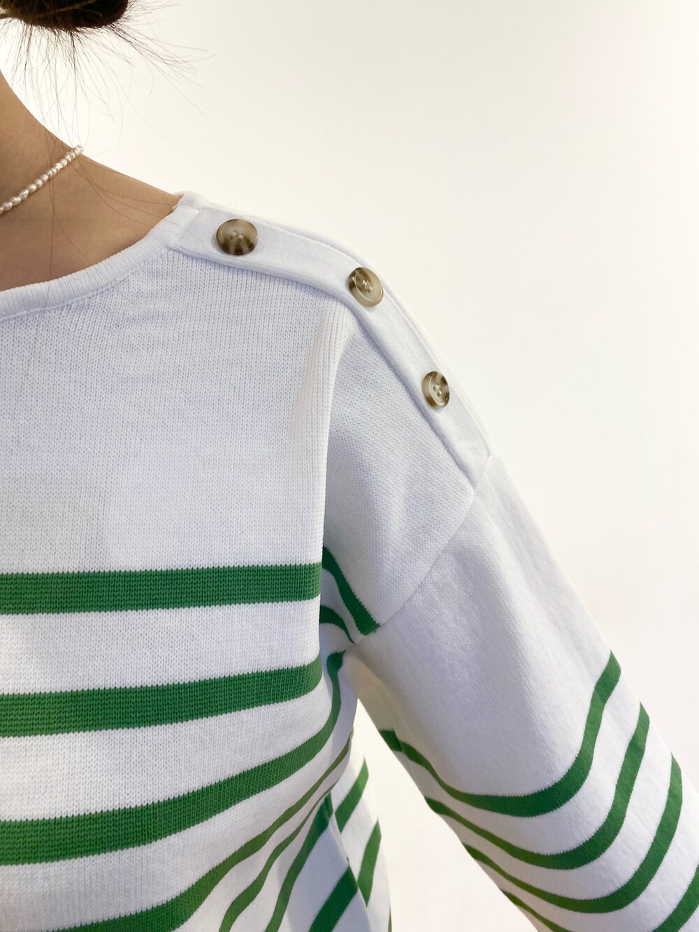 ブラウン系のトートバッグ、グリーン系のニット/セーター、グリーン系のデニムパンツを着用したレディースの冬コーディネートの2枚目の写真