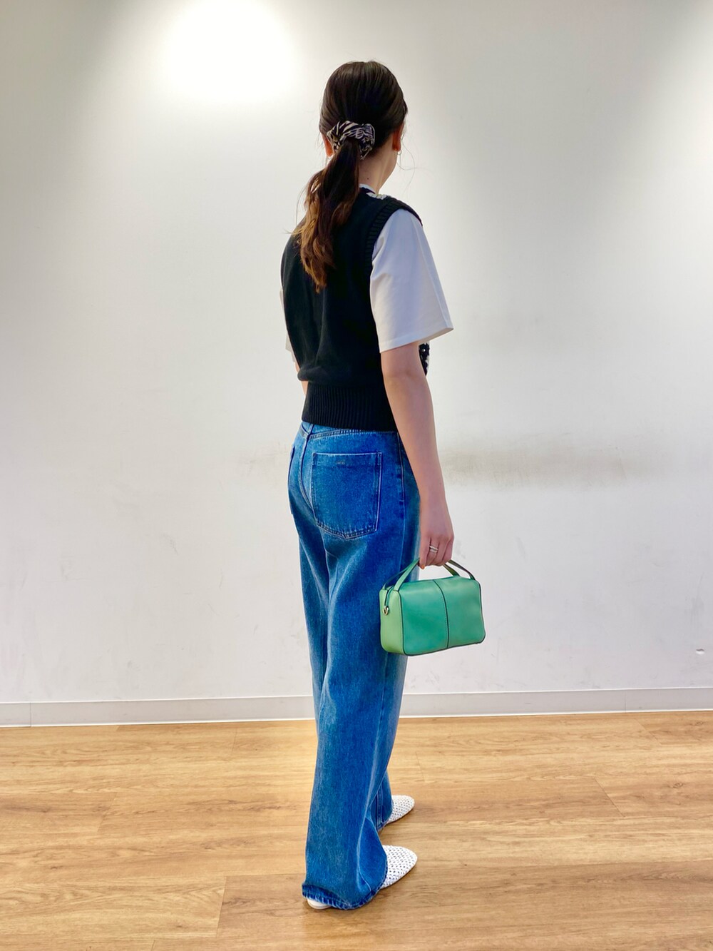 ブルー系のデニムパンツ、グリーン系のショルダーバッグ、ホワイト系のその他シューズを着用したレディースの春コーディネートの2枚目の写真
