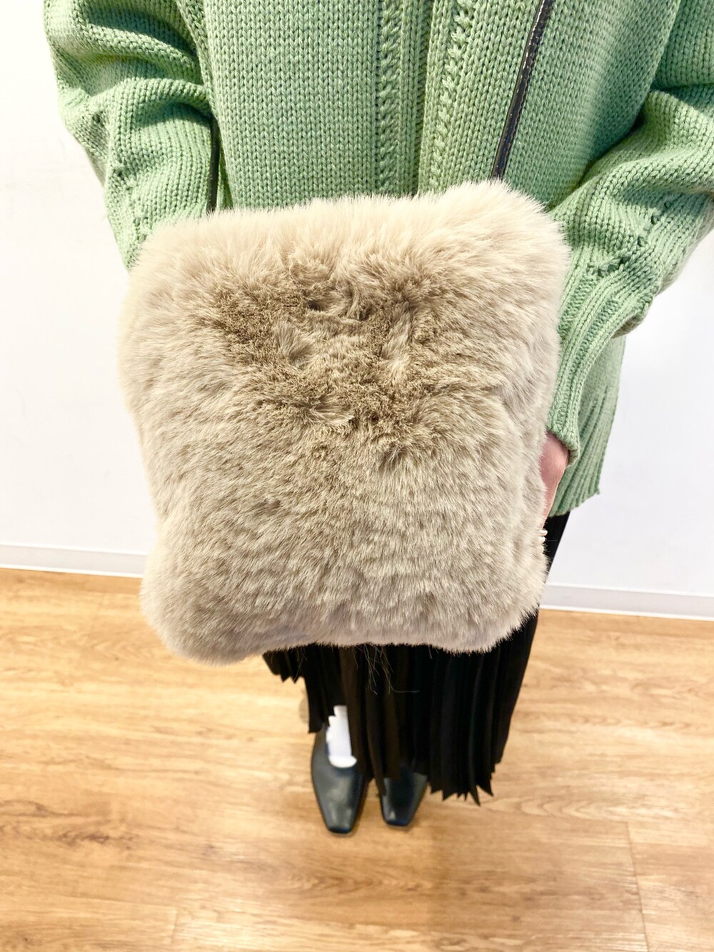 グリーン系のニット/セーター、ベージュ系のショルダーバッグ、ブラック系のスカートを着用したレディースの冬コーディネートの5枚目の写真