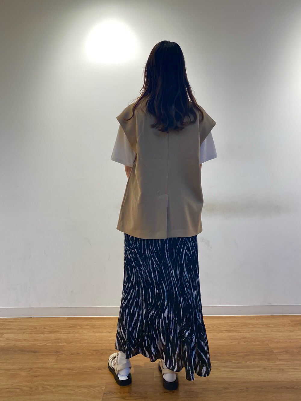 ブラック系のスカート、ベージュ系のその他アウター、ホワイト系のサンダルを着用したレディースの春コーディネートの2枚目の写真