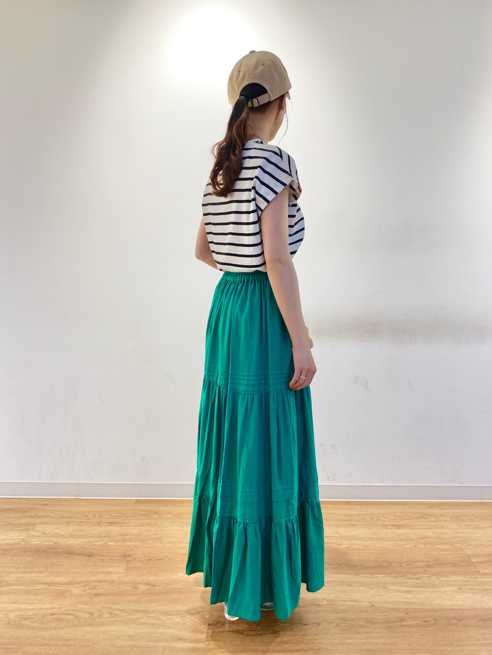 ホワイト系のTシャツ/カットソー、グリーン系のスカート、グリーン系のサンダルを着用したレディースの春コーディネートの2枚目の写真