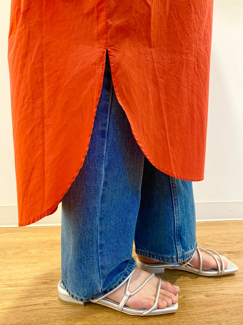 レッド系のワンピース、ベージュ系のトートバッグ、ブルー系のデニムパンツを着用したレディースの春コーディネートの5枚目の写真