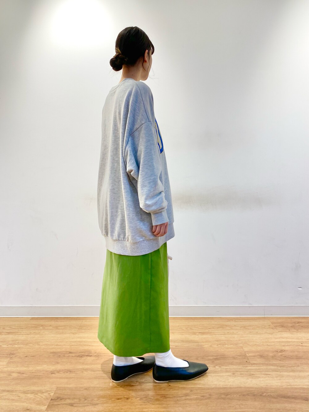 グレー系のスウェット、グリーン系のスカート、ホワイト系のショルダーバッグを着用したレディースの冬コーディネートの3枚目の写真